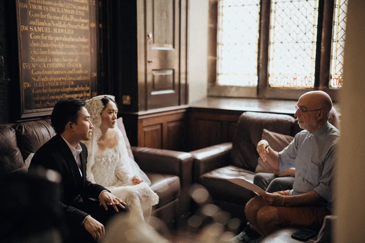 A couple speaking with the officiant before their Manchester church ceremony