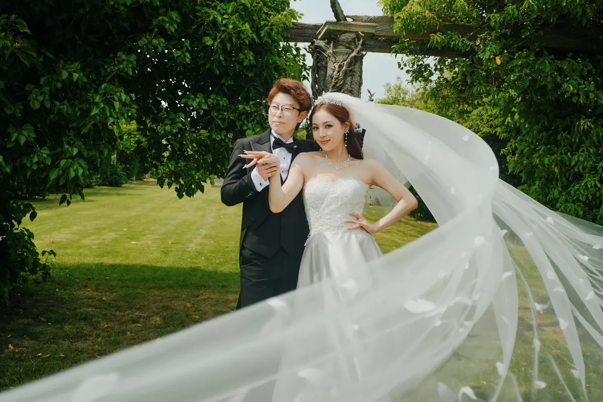 A couple beneath a moving veil in an English summer garden